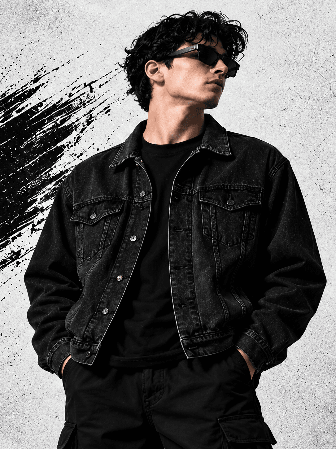 Model wearing a black denim jacket over a black T-shirt with utility trousers and sunglasses